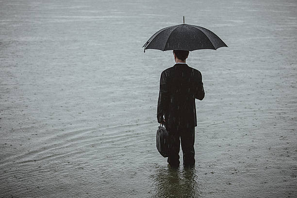 bell'uomo che indossa la tuta e tiene l'ombrello durante la pioggia - camminare nellacqua foto e immagini stock