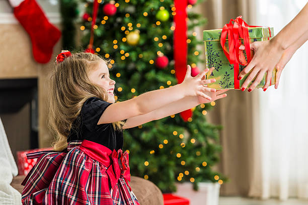 istock Smiling little girl reaching for Christmas present 594041798
