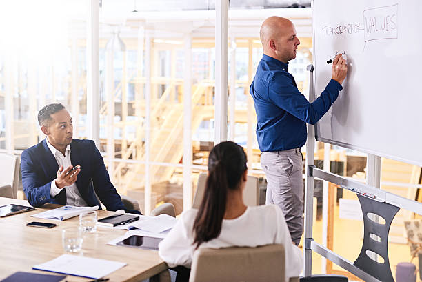 istock Young caucasian businessman writing company values on white board 594047258
