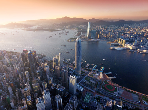 Dramatic skyline of Hong Kong Island and busy ships navigates across the Victoria Harbour during beautiful sunset on a non air-polluted day.