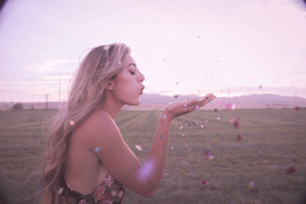 Woman blowing stars confetti in field