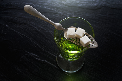 absinthe in pontarlier glass and spoon with sugar cubes