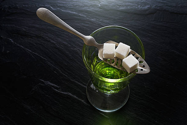 absinthe in pontarlier glass on dark slate absinthe in pontarlier glass and spoon with sugar cubes absinthe spoon stock pictures, royalty-free photos & images