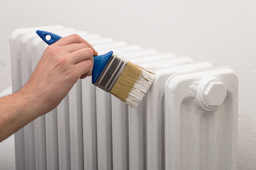 Painting old white radiator with brush