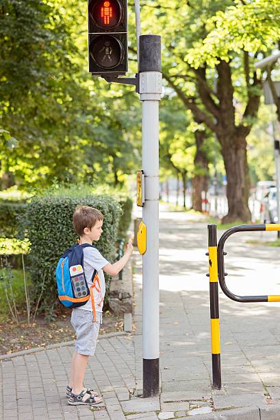 istock Little 7 years schoolboy pressing a button on traffic lights 594078000