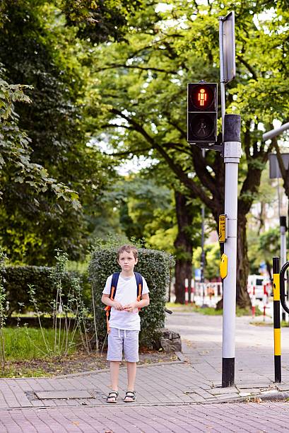 istock Little 7 years schoolboy waiting for green light 594078182