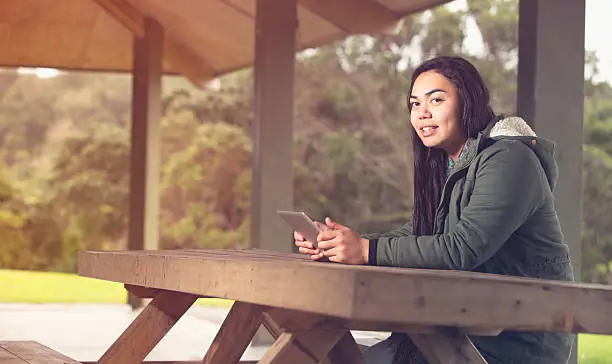 Maori girl using tablet in an outdoor setting,