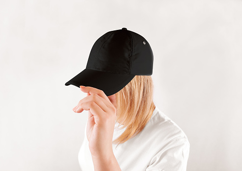 Blank black baseball cap mockup template, wear on women head, isolated, side view. Woman in clear grey hat and t shirt uniform mock up holding visor of caps. Cotton basebal cap design on delivery guy.