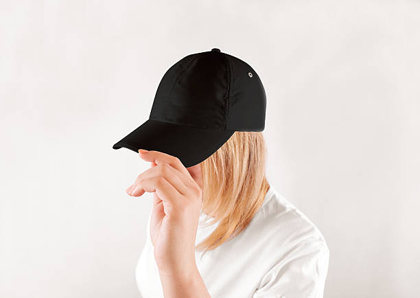 Blank black baseball cap mockup template, wear on women head Blank black baseball cap mockup template, wear on women head, isolated, side view. Woman in clear grey hat and t shirt uniform mock up holding visor of caps. Cotton basebal cap design on delivery guy. woman wearing baseball cap stock pictures, royalty-free photos & images