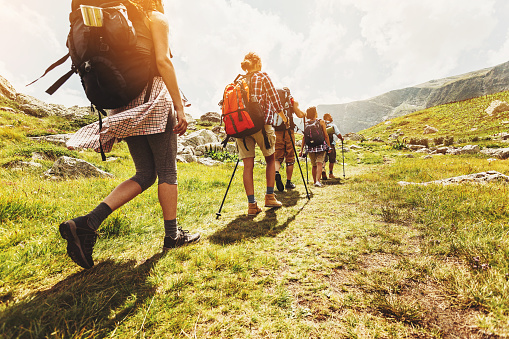 Group of hikers walking in line on a footpath in the mountain, with copy space