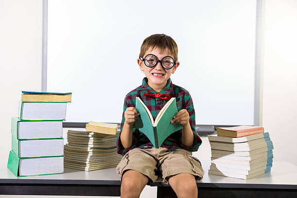 istock Portait of boy holding book while sitting in classroom 594450788
