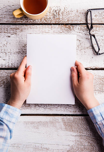 istock Unrecognizable woman holding empty paper sheet. Studio shot. 594454368