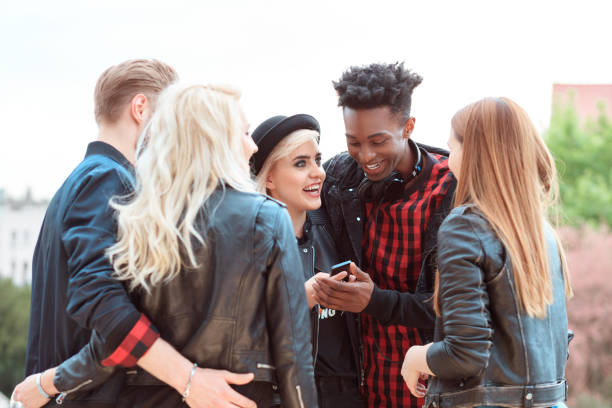 istock Multi ethnic group of friends using mobiles outdoors 594455244