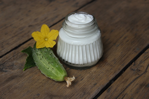 Organic face cream cucumber with flower on wooden boards