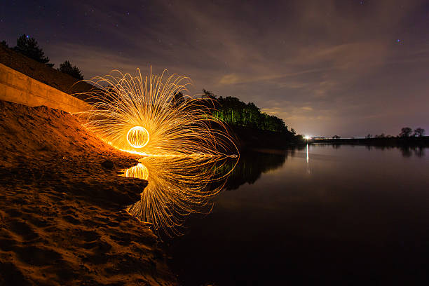 istock Sparks from the burning steel wool on the river bank 594456424