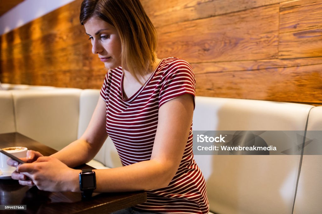 Woman using cellphone at table Young woman using cellphone while sitting at table in restaurant Adult Stock Photo