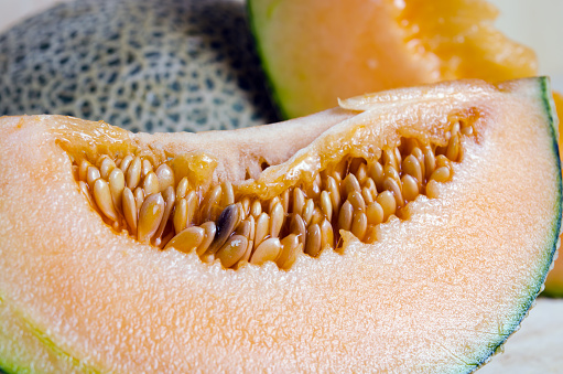 Cucumis melo or melon with half and seeds on wooden plate (Other names are cantelope, cantaloup, honeydew, Crenshaw, casaba,  Persian melon, and Santa Claus or Christmas melon)