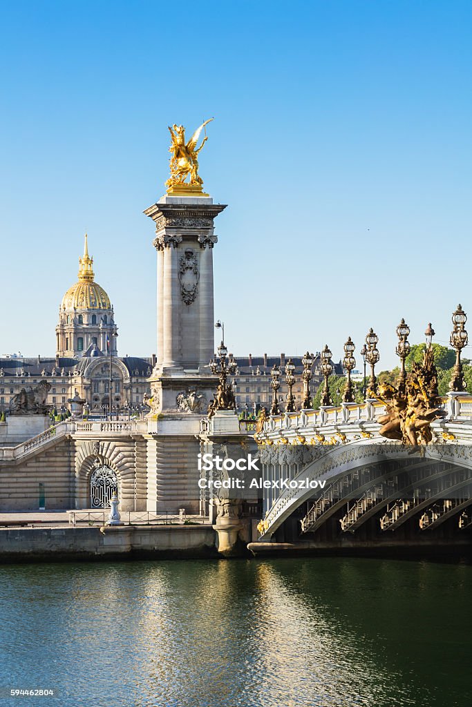 Alexandre III Bridge with Hotel des Invalides, Paris, France Alexandre III bridge and Hotel des Invalides in the background in the summer morning. Bridge decorated with ornate Art Nouveau lamps and sculptures. Paris - France Stock Photo