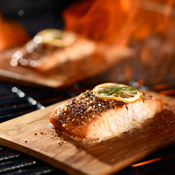 istock salmon fillets cooking on cedar planks on grill 594463352