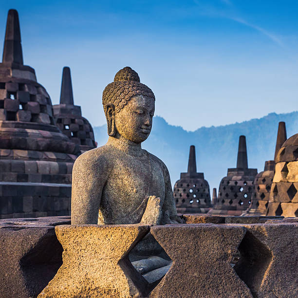 istock Ancient Buddha statue and stupa at Borobudur temple 594464056