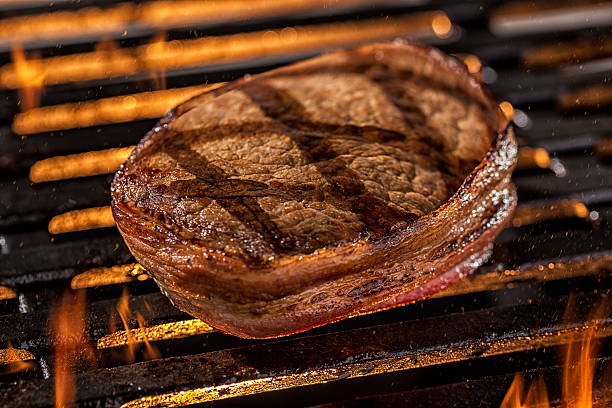 istock Grilling Filet Mignon Steak on a grill with Fire 594464094