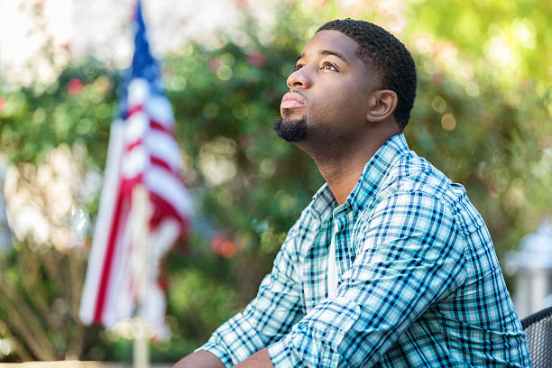 african american man sad after receiving bad news holding flag - depression sadness usa american flag imagens e fotografias de stock