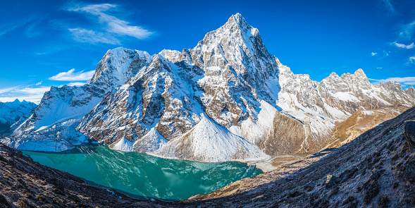 The snowy ridges and icy summit of Cholatse (6440m) soaring over the dramatic north face reflecting in the turquoise waters of the glacial lake below, deep in the remote Himalaya mountain wilderness of the Everest National Park, a UNESCO World Heritage Site, Nepal.
