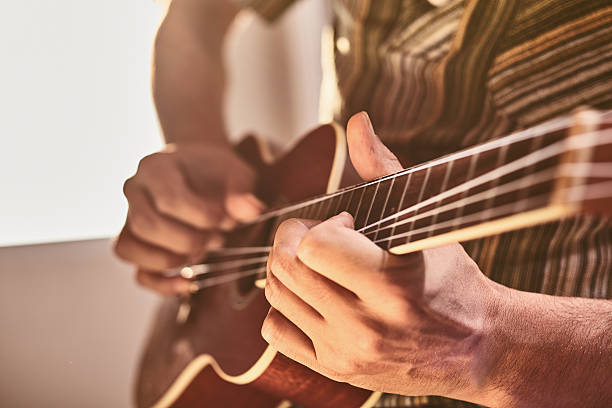 uomo seduto per finestra giocando ukelele - uke foto e immagini stock