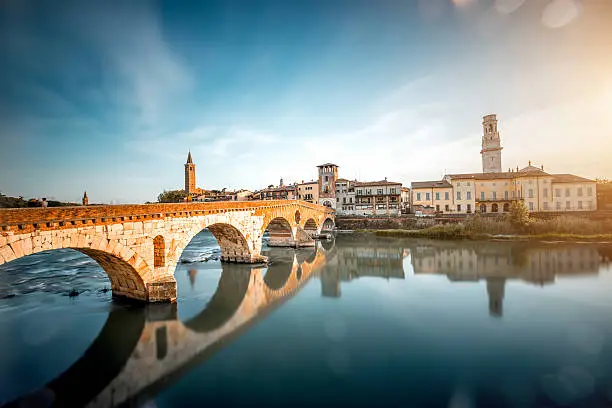 Verona cityscape view on the riverside with historical buildings and towers on the sunset