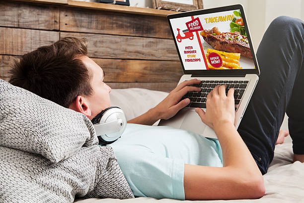hombre usando una computadora portátil para pedir comida por internet. - red meat fotografías e imágenes de stock