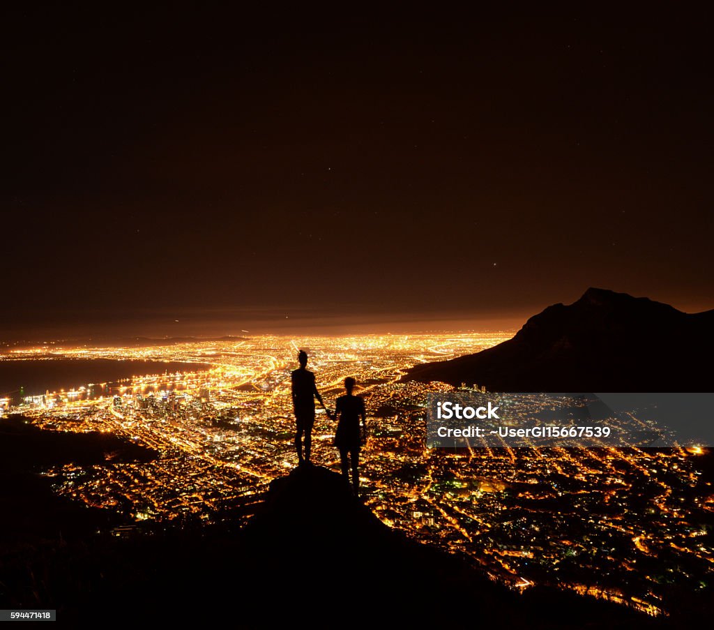 City Lights Two friend holding hand looking over the city lights of Cape Town from the top of the mountain - South Africa City Stock Photo