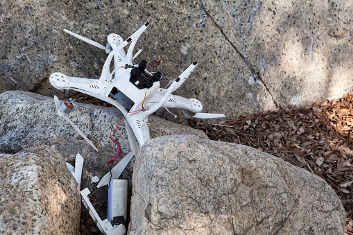 Altadena, CA, USA – August 21, 2016: Crashed drone is broken and wedged among rocks with pieces scattered nearby.