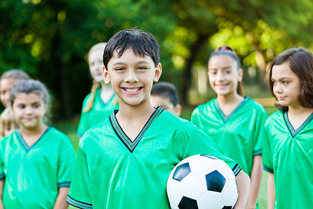 симпатичный футболист-мужчина с товарищами по команде - playing field kids soccer goalie soccer player стоковые фото и изображения