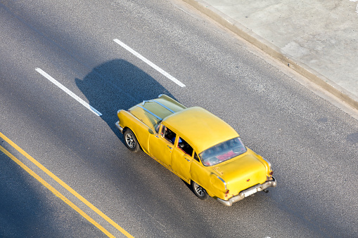 Yellow vintage American car speeding along the Malecon in Havana, Cuba, motion blur, 50 megapixel image.