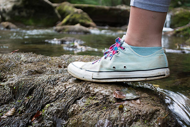 istock Girls foot stepping on a mossy rock 594475280