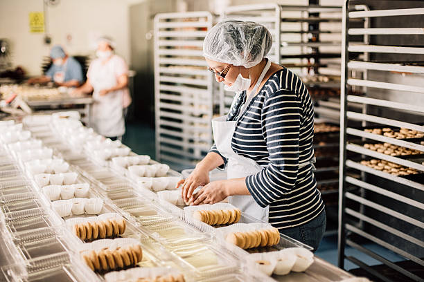frau arbeitet bei bakery workshop - lebensmittelverarbeitung stock-fotos und bilder