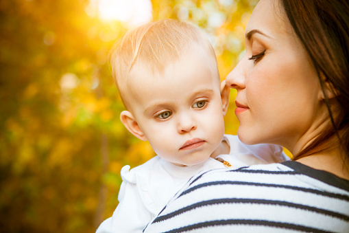 Young mother with her baby daughter in autumn park