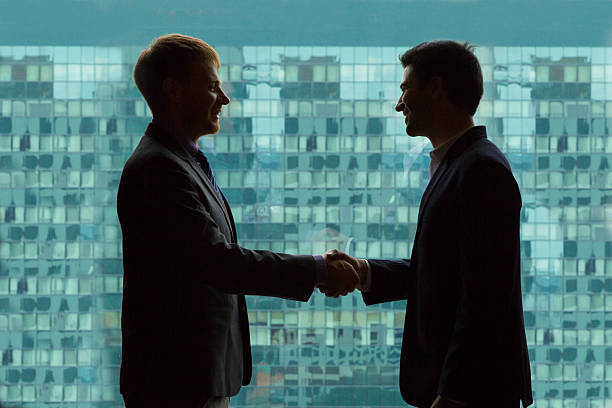 istock Silhouettes of Businessmen Shaking Hands 594478548