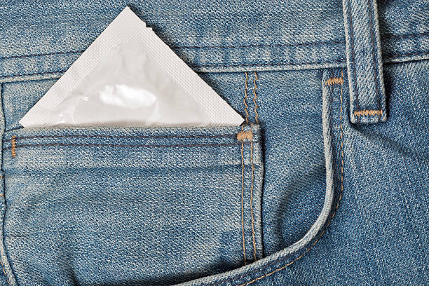 préservatif dans la poche d’un jean bleu gros plan - sex condom jeans horizontal photos et images de collection
