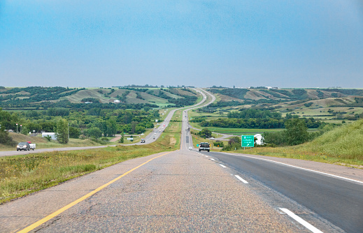 View of Highway 11 in the province of Saskatchewan.  The highway goes down through the Lumsden Valley and the town of Lumsden of the way to the provincial capital of Regina.  Once can see both sides of this divided highway as it goes into the valley and then up the far side.  Traffic can be seen moving in both directions on Highway 11.