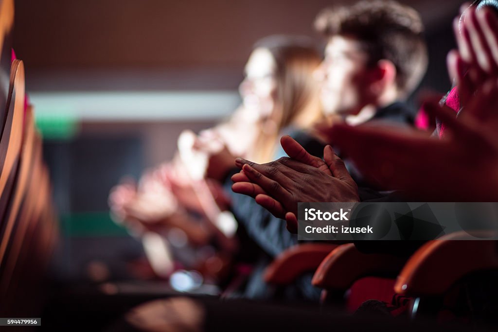 People in the theater, close up of clapping hands People in the theater. Side view. Dark tone. Focus on clapping hands. Theatrical Performance Stock Photo