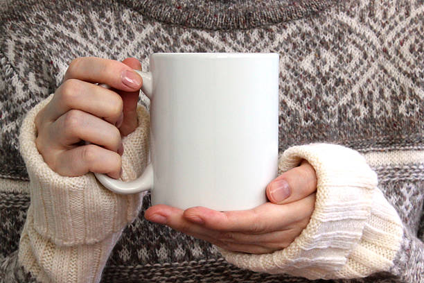 girl in a warm sweater is holding white mug in hands. - white coffee mug imagens e fotografias de stock