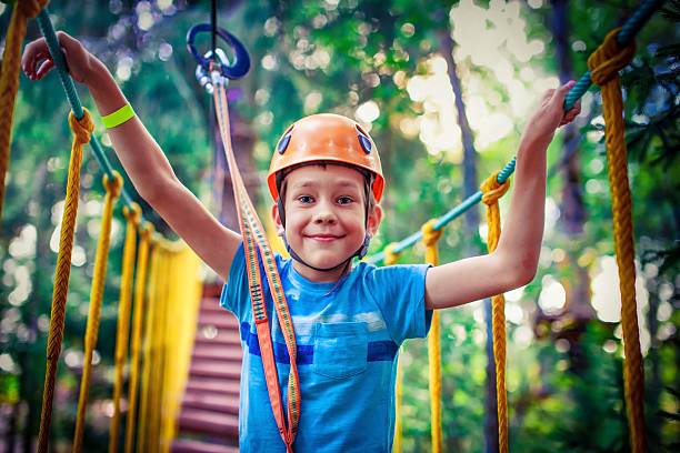 happy boy on the zipline proud of his courage the child in the high wire park. hanging bridge. HDR summer camp photos stock pictures, royalty-free photos & images