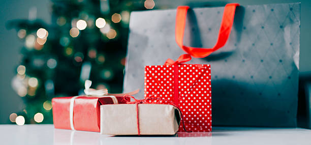 bolsa de la compra y regalos de navidad frente al árbol de navidad - holiday shopping fotografías e imágenes de stock