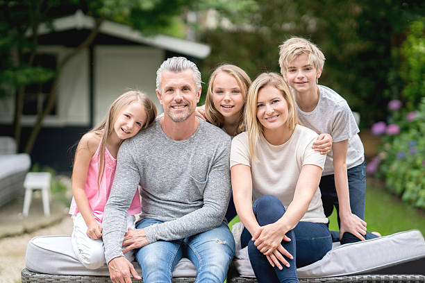 Portrait of a happy family in the garden of their home and looking at the camera smiling