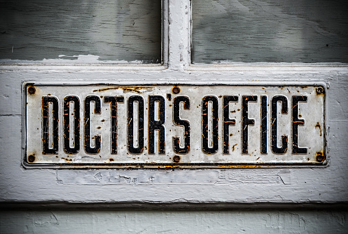 A Doctor's Office Sign On A Rustic Wooden Door