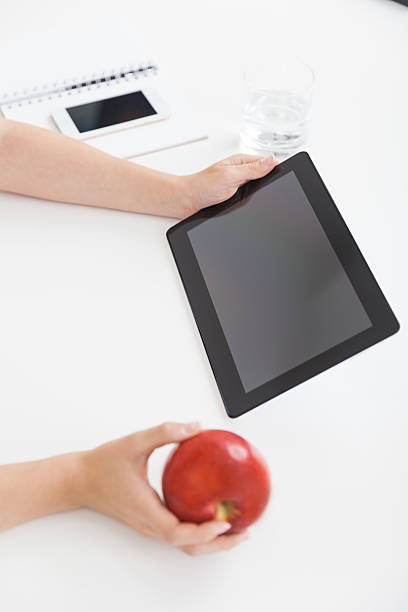 istock Woman holding tablet and apple 594483830