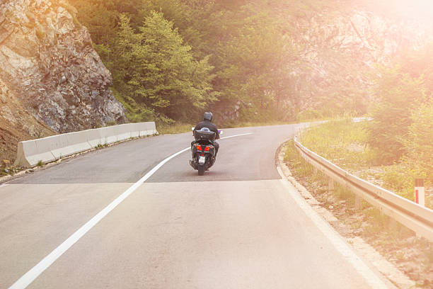 istock Biker riding motorcycle on an empty road at sunset 594485116