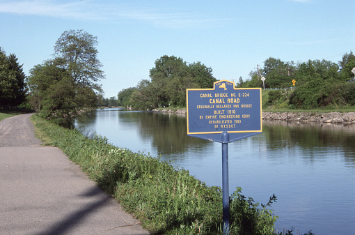 Erie Canal with historic bridge sign and towpath. 