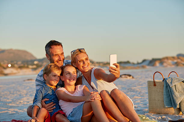 family posing for selfie on beach - beach two parent family couple family imagens e fotografias de stock